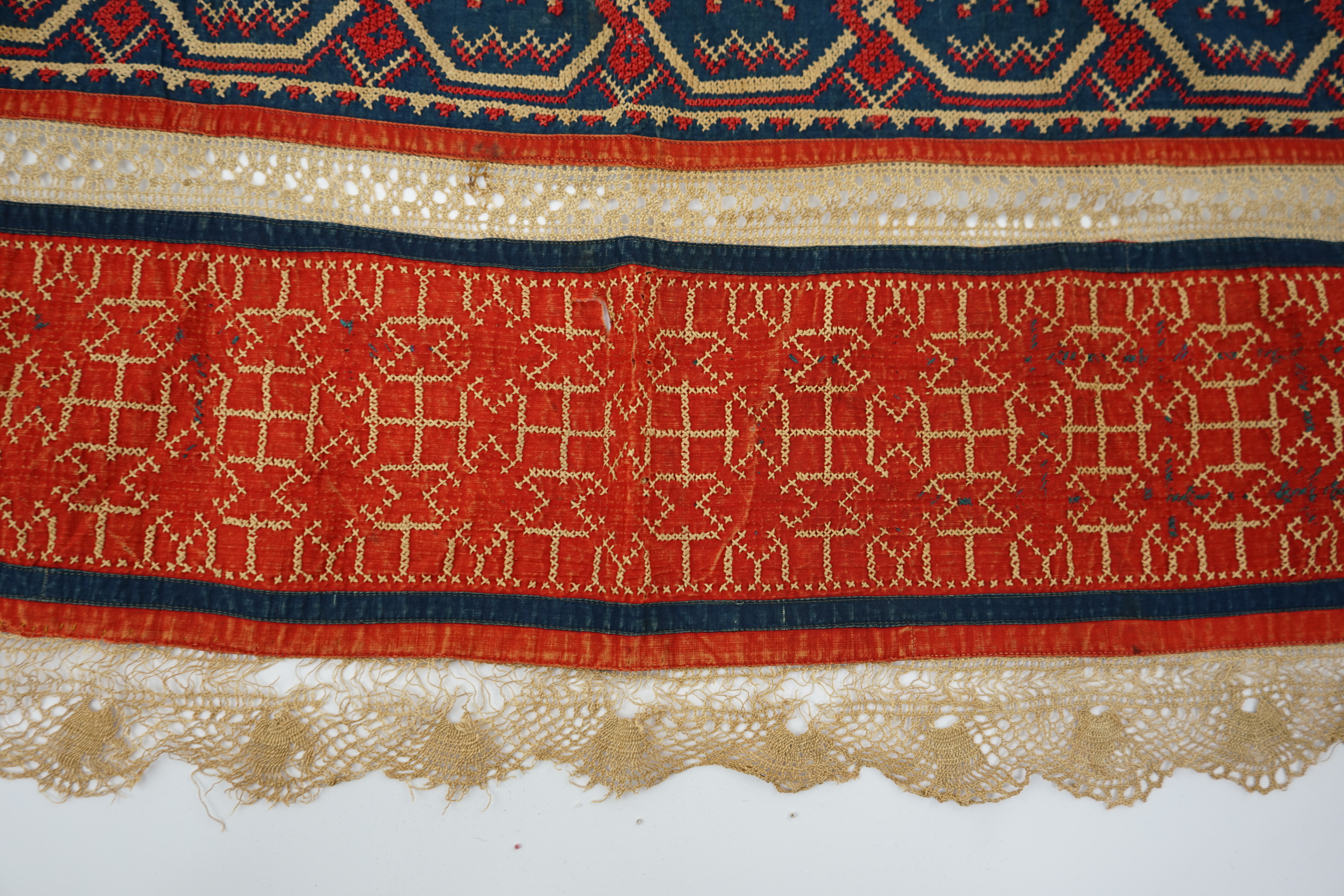 An Eastern European, possibly Ukrainian, apron and a Norwegian beaded bodice front, with child’s cap, the apron worked in rows of coloured cotton, embroidered with cross stitch patterns and lace insertions, the bodice, b